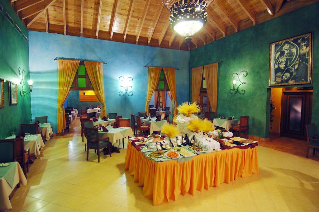 Impressive Punta Cana Hotel Exterior photo The photo depicts a vibrant restaurant interior. The walls are a rich turquoise color, and the ceiling features exposed wooden beams. There are large windows draped with bright yellow curtains, allowing natural light to enter the space. 

In the cent