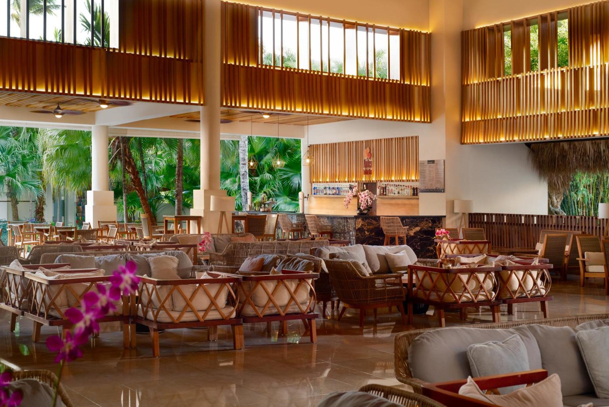 Impressive Punta Cana Hotel Exterior photo The photo shows a spacious and elegantly designed restaurant or lounge area. It features a mix of comfortable seating, including sofas and armchairs arranged around tables. The decor incorporates warm wooden elements and luxurious lighting, creating 