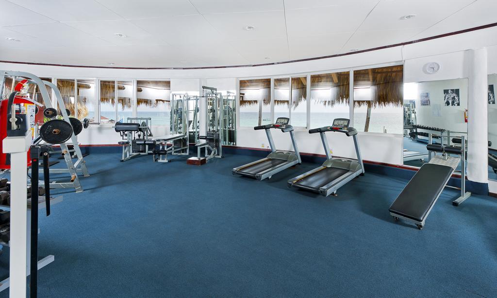 Impressive Punta Cana Hotel Exterior photo The photo shows a fitness room equipped with several exercise machines. There are two treadmills positioned side by side, along with a weight machine in the background. Additionally, there appears to be a flat bench for workouts. The walls are mirror